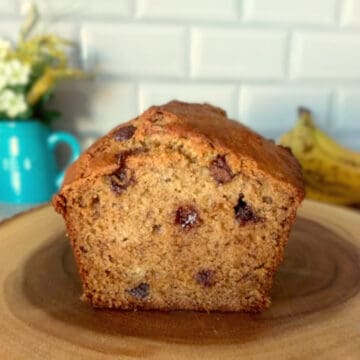 honey banana bread on a wood log. The bread is cut in half and is showing the chocolate chips inside.