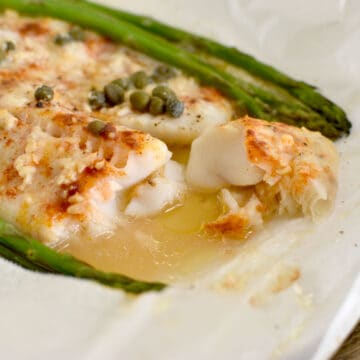 White fish with asparagus and capers in a parchment paper bag