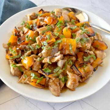 sliced chicken thighs and yellow bell pepper with honey balsamic glaze on a plate with a spoon.