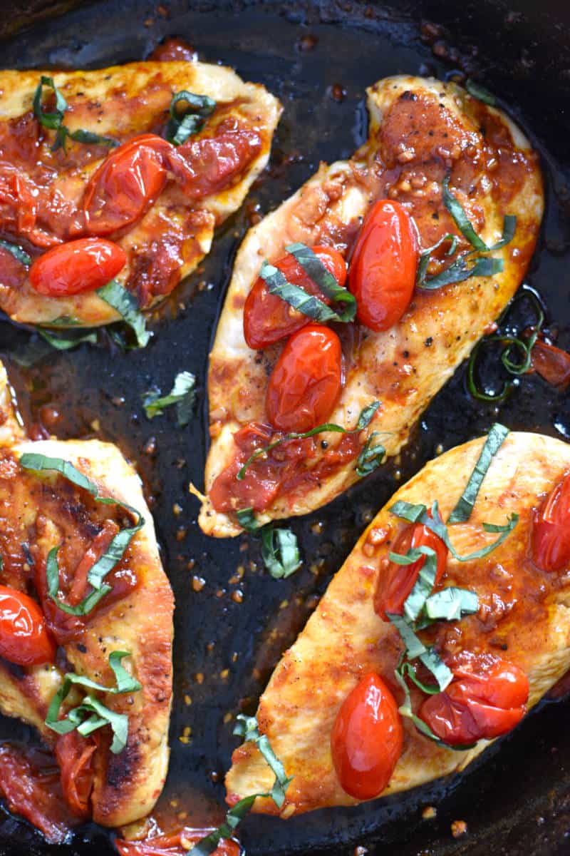 Pan seared chicken breasts with grape tomatoes and basil in a iron skillet