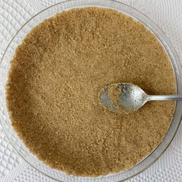 graham cracker crust, not baked, in a pie plate with a spoon