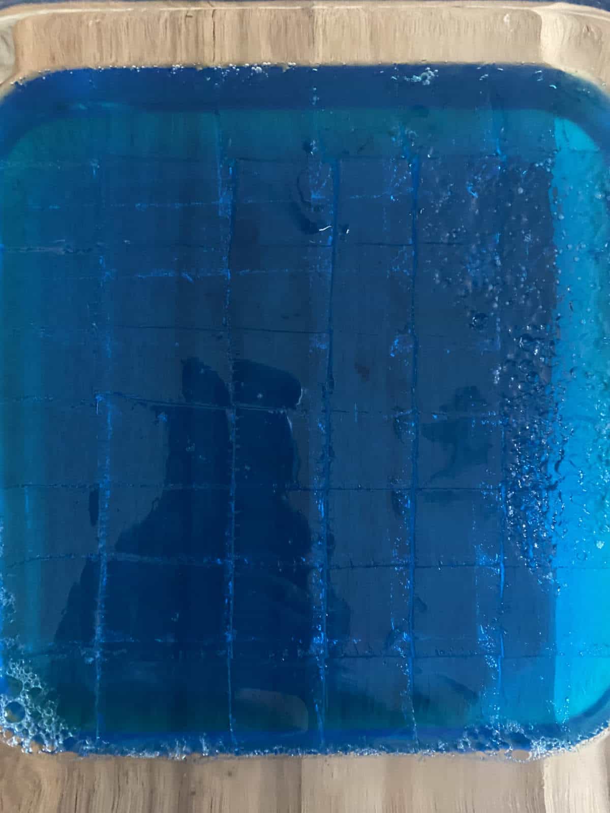 Blue Jell-O with horizontals and vertical line cuts, making squares