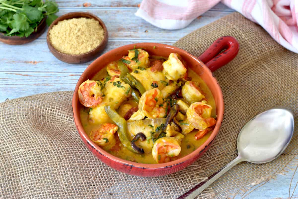 fish, shrimp and vegetables with a coconut sauce in a clay pan