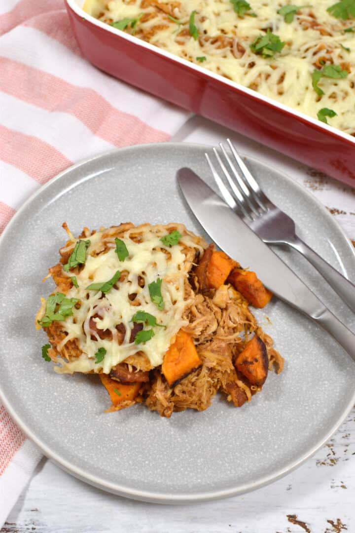 sweet potatoes with barbecue shredded chicken and cheese on a plate with fork and knife