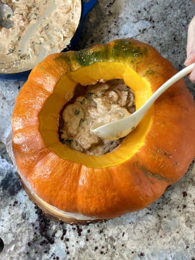 filling the pumpkin with the chowder using a laddle