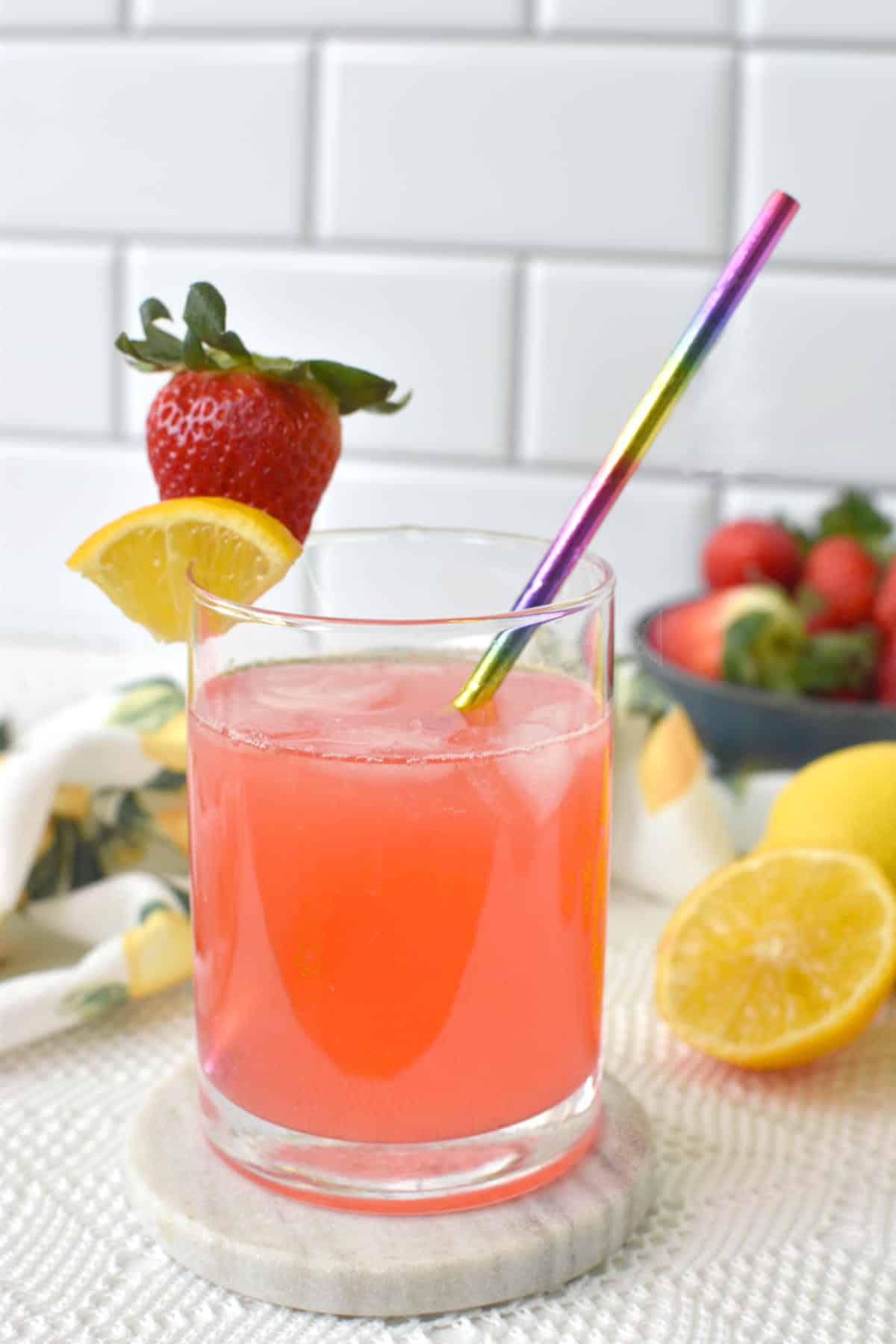 homemade strawberry pink lemonade in a cup with straw, ice, and garnish.