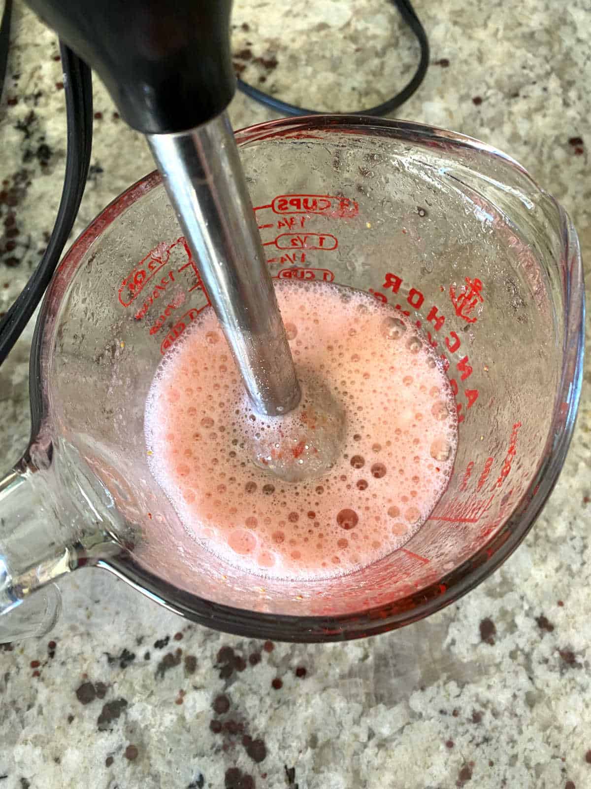 blending strawberries and lemon juice with an immersion blender.