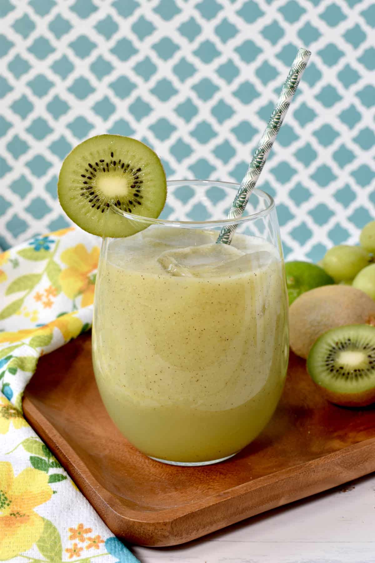 smootie with a kiwi slice garnishing and a paper straw inside the cup