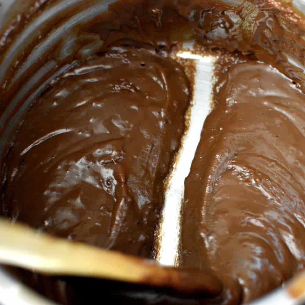 spoon dividing brigadeiro in pan into 2 parts, being able to see the bottom of the pan.