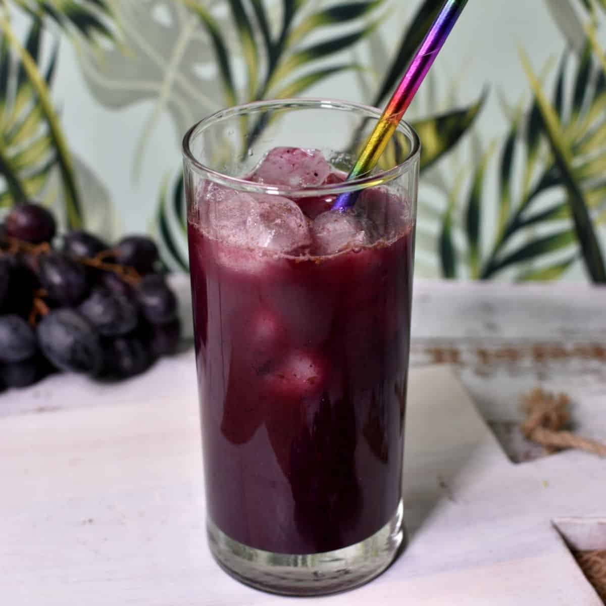 suco de uva caseiro no copo com gelo e canudo de papel.