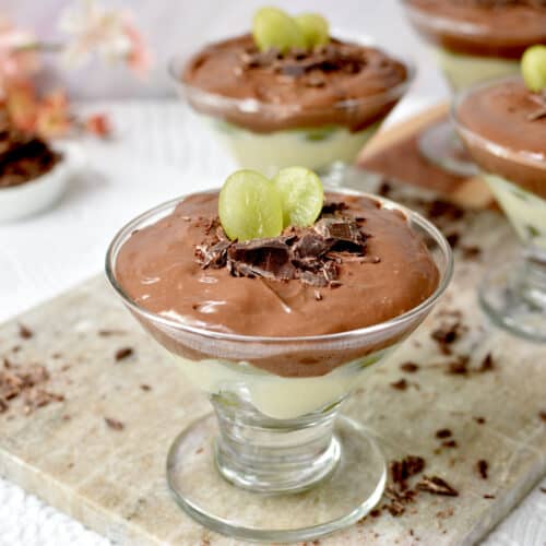 taça de vidro com uvas, creme de baunilha e creme de chocolate com raspas de chocolate e uvas decorando.